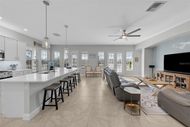 living room featuring sink, french doors, and ceiling fan