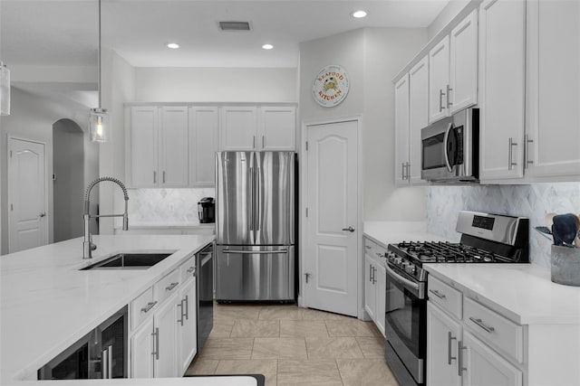 kitchen with hanging light fixtures, sink, white cabinets, and appliances with stainless steel finishes