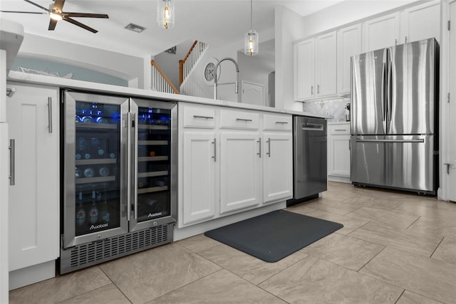 kitchen featuring appliances with stainless steel finishes, pendant lighting, white cabinetry, wine cooler, and backsplash