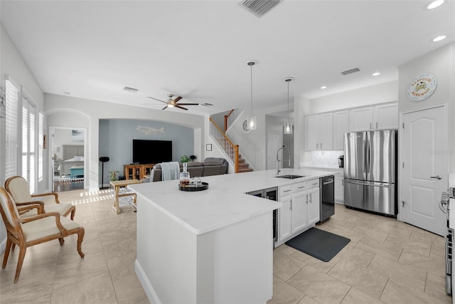 kitchen with appliances with stainless steel finishes, a kitchen island with sink, sink, and white cabinets