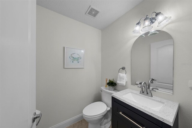 bathroom featuring vanity, a textured ceiling, and toilet