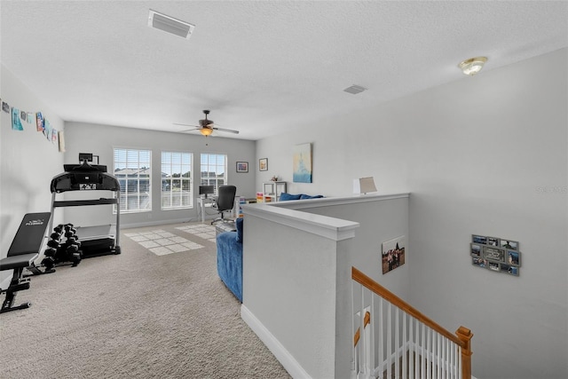 interior space featuring light carpet, ceiling fan, and a textured ceiling