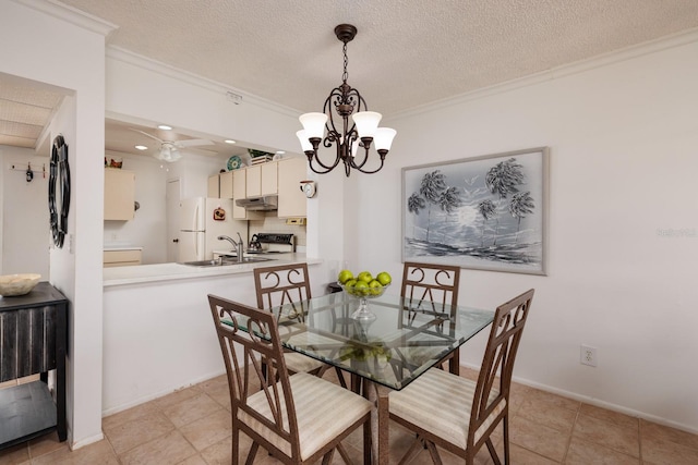 tiled dining area with a textured ceiling, ceiling fan with notable chandelier, ornamental molding, and sink