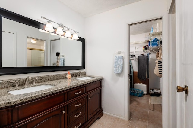 bathroom with tile patterned flooring, vanity, a shower with shower door, and a textured ceiling