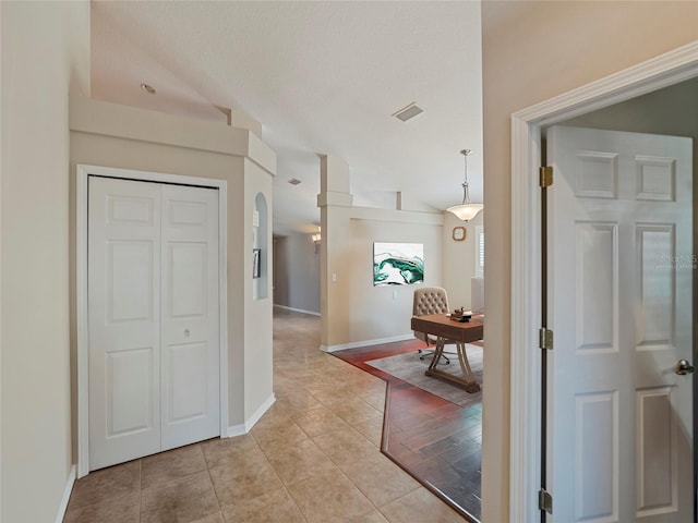 hall featuring lofted ceiling and light tile patterned floors