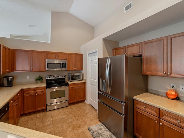 kitchen with vaulted ceiling, appliances with stainless steel finishes, and light tile patterned flooring