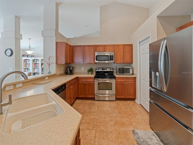 kitchen with lofted ceiling, sink, appliances with stainless steel finishes, hanging light fixtures, and kitchen peninsula