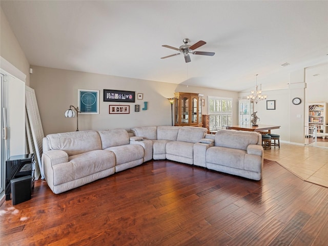 living room featuring dark wood-type flooring and ceiling fan with notable chandelier