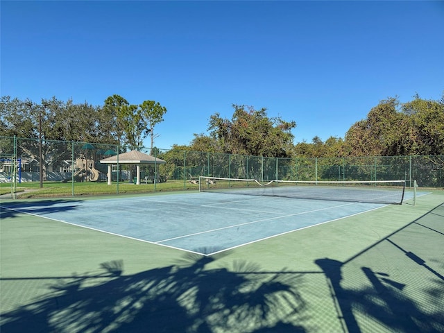 view of tennis court featuring a playground and a gazebo