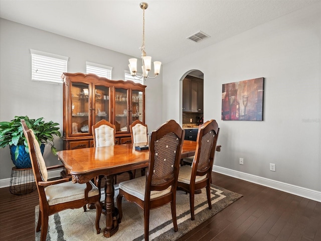 dining area featuring dark wood-type flooring and an inviting chandelier