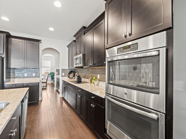 kitchen featuring dark brown cabinetry, dark hardwood / wood-style flooring, a textured ceiling, and appliances with stainless steel finishes