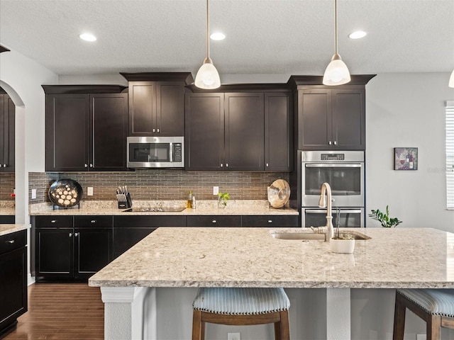 kitchen with sink, decorative light fixtures, a center island with sink, and appliances with stainless steel finishes