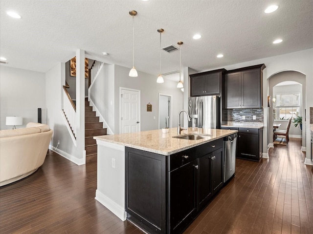 kitchen featuring appliances with stainless steel finishes, sink, hanging light fixtures, and an island with sink