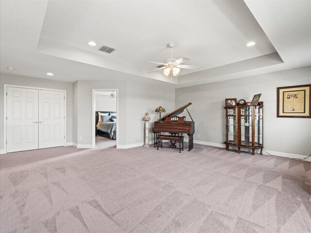 miscellaneous room featuring light colored carpet, ceiling fan, and a tray ceiling