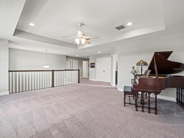 miscellaneous room with a tray ceiling, ceiling fan, carpet floors, and a textured ceiling