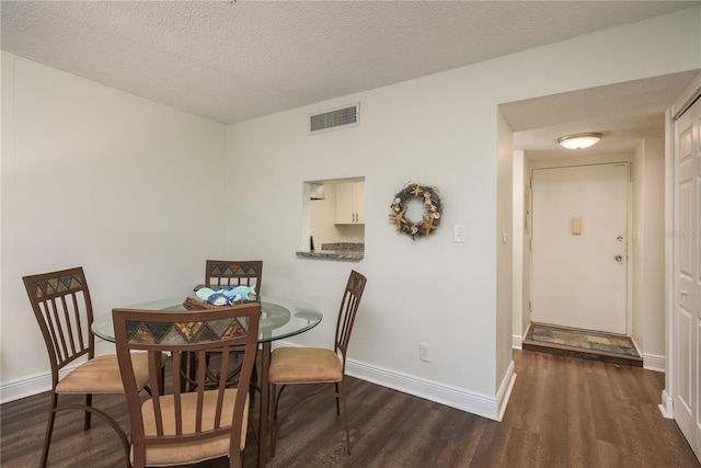 dining space with dark hardwood / wood-style flooring and a textured ceiling