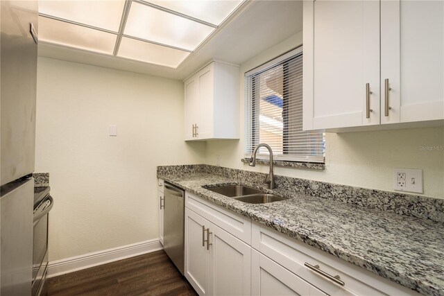 kitchen with sink, light stone countertops, dark hardwood / wood-style flooring, white cabinetry, and stainless steel appliances