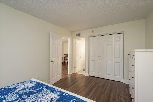 unfurnished bedroom with dark hardwood / wood-style floors, a textured ceiling, and a closet