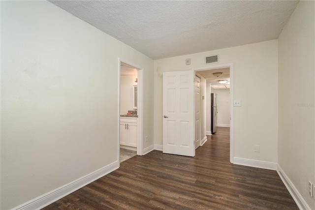 spare room featuring a textured ceiling and dark hardwood / wood-style floors