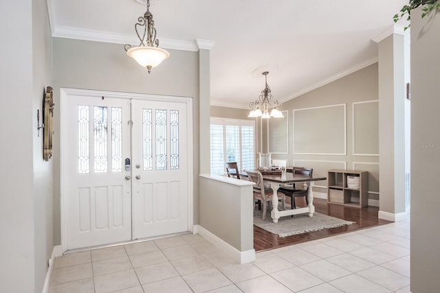 tiled foyer entrance with lofted ceiling, crown molding, and a notable chandelier