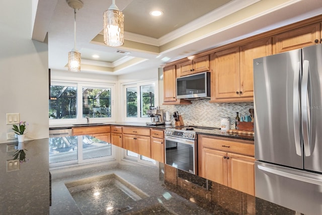 kitchen with sink, dark stone countertops, pendant lighting, appliances with stainless steel finishes, and ornamental molding