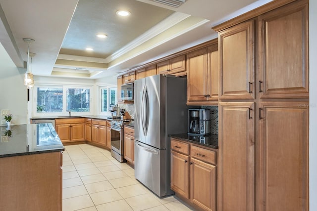 kitchen with dark stone countertops, sink, appliances with stainless steel finishes, and a tray ceiling