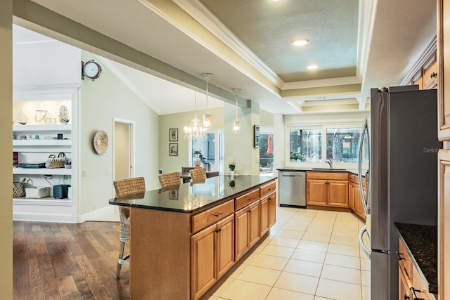 kitchen with a kitchen breakfast bar, light wood-type flooring, appliances with stainless steel finishes, sink, and a kitchen island