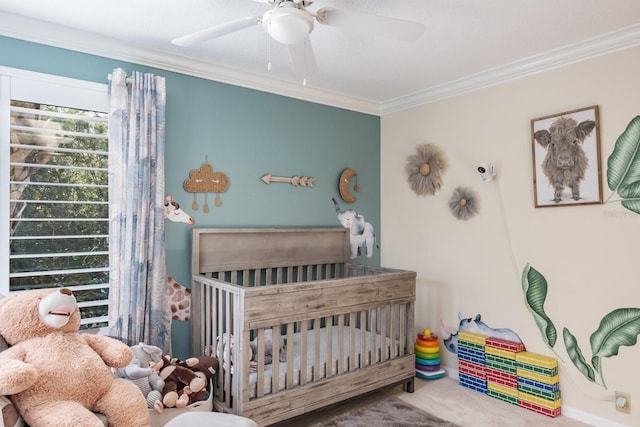 bedroom with ceiling fan, a crib, and ornamental molding