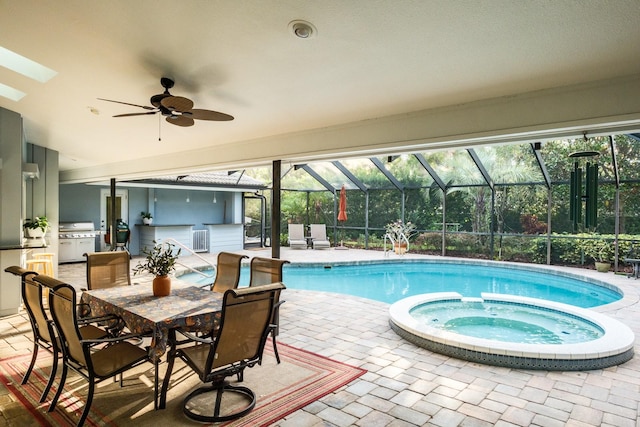 view of swimming pool with ceiling fan, a lanai, an in ground hot tub, a patio area, and exterior kitchen