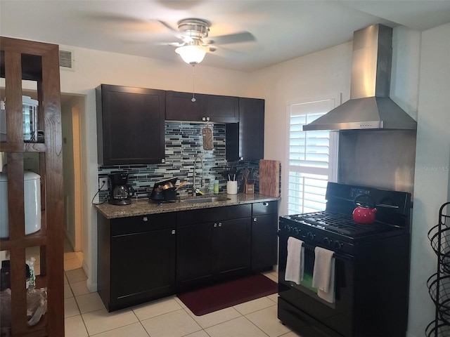 kitchen featuring light stone countertops, sink, wall chimney exhaust hood, backsplash, and black gas stove