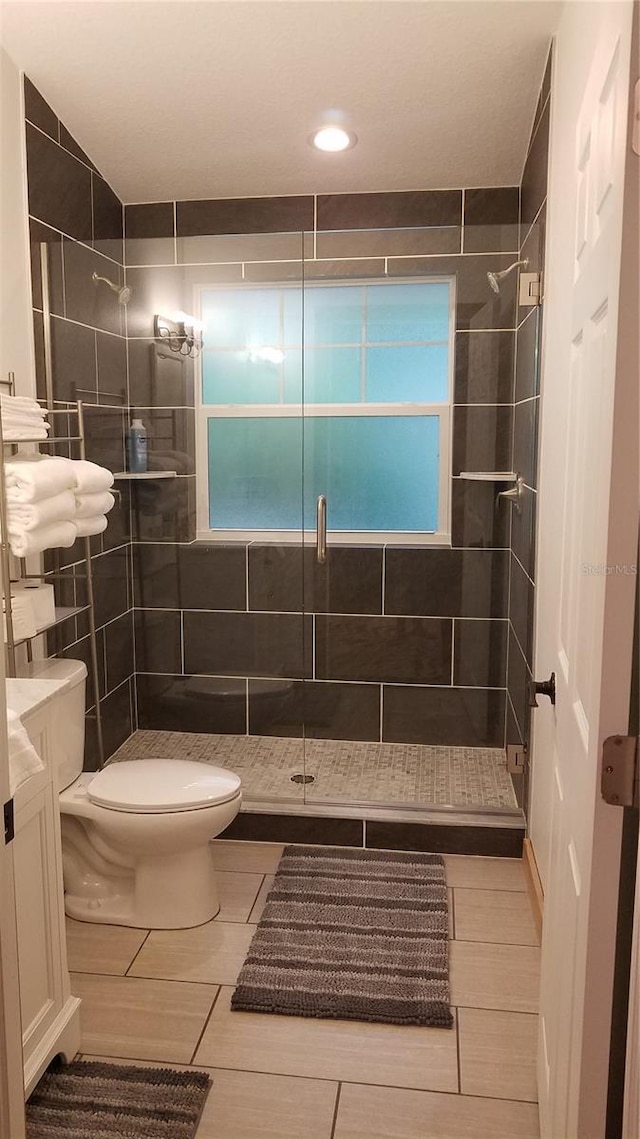 bathroom with tile patterned flooring, vanity, toilet, and walk in shower