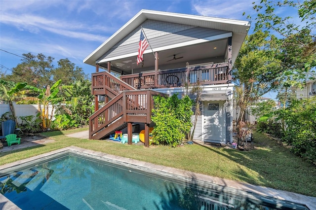 rear view of house featuring a swimming pool side deck, ceiling fan, and a yard