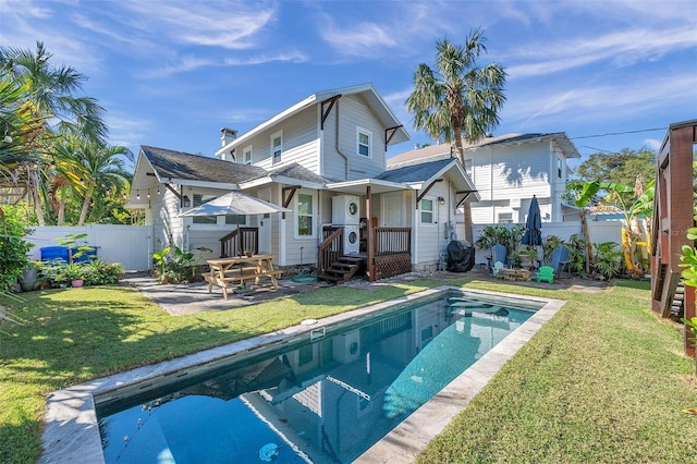 back of house featuring a fenced in pool and a yard