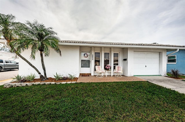 view of front of property featuring a garage, driveway, a front lawn, and stucco siding