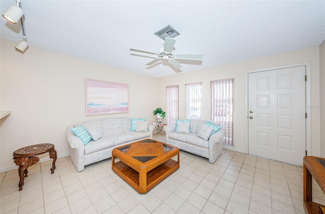 living room featuring a textured ceiling, ceiling fan, light tile patterned flooring, visible vents, and baseboards