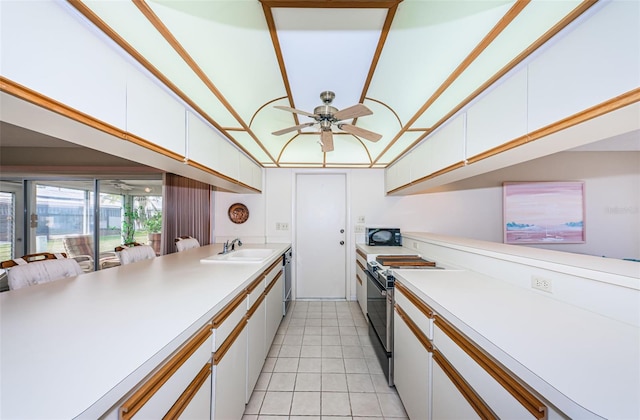 kitchen with electric range, white cabinetry, light countertops, and a sink