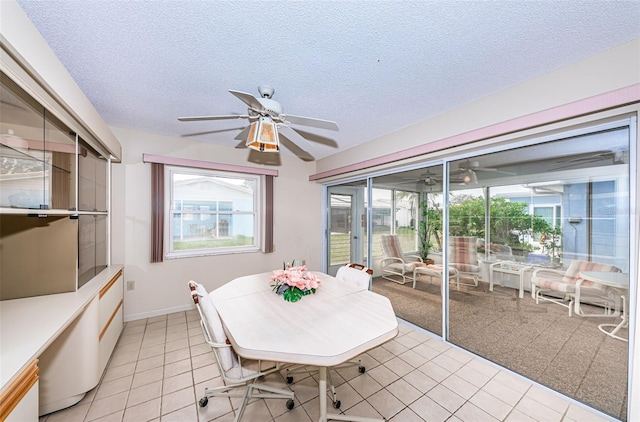 dining area featuring a textured ceiling, light tile patterned flooring, a ceiling fan, and baseboards