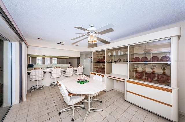 dining room with a ceiling fan, a textured ceiling, and light tile patterned flooring