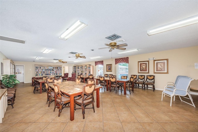 dining room with a textured ceiling, light tile patterned floors, visible vents, and a ceiling fan