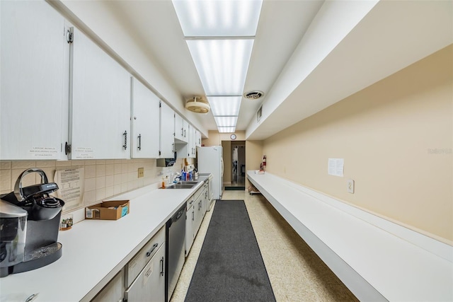 kitchen featuring white cabinets, light countertops, freestanding refrigerator, decorative backsplash, and dishwasher