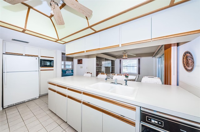 kitchen featuring a sink, black appliances, light countertops, and white cabinetry