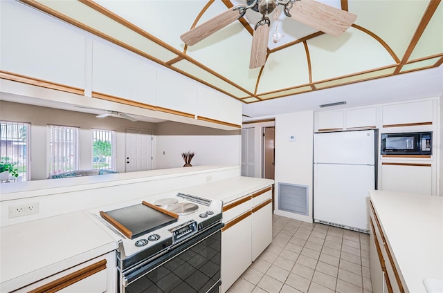 kitchen featuring range with electric stovetop, light countertops, freestanding refrigerator, white cabinetry, and black microwave