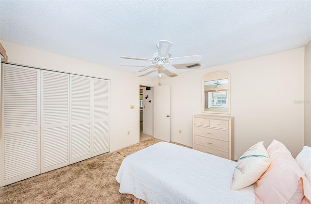 bedroom featuring visible vents, light colored carpet, ceiling fan, a textured ceiling, and a closet