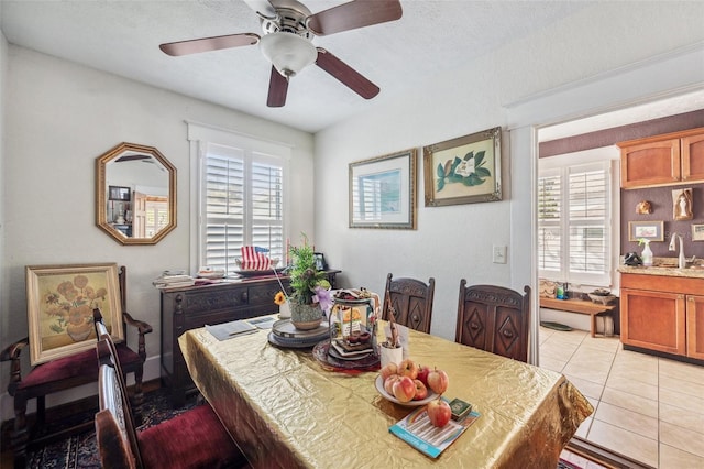 dining room with light tile patterned floors, a textured ceiling, ceiling fan, and sink