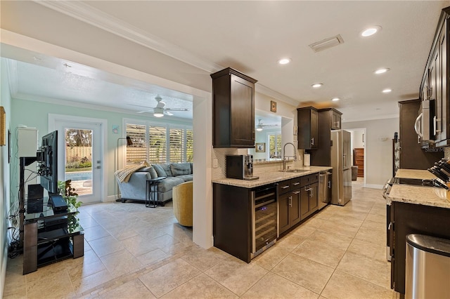 kitchen with sink, beverage cooler, stainless steel appliances, light stone counters, and crown molding