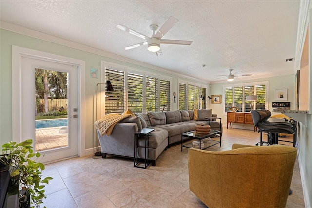 living room with plenty of natural light, ceiling fan, crown molding, and a textured ceiling