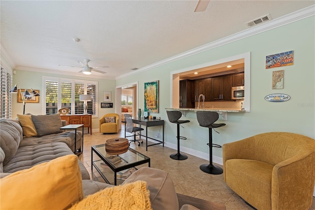 living room featuring ceiling fan, ornamental molding, sink, and light tile patterned floors