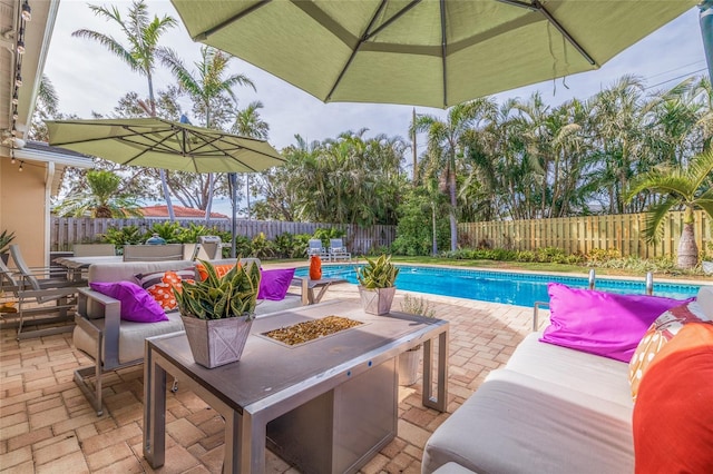 view of swimming pool featuring a patio and an outdoor living space with a fire pit