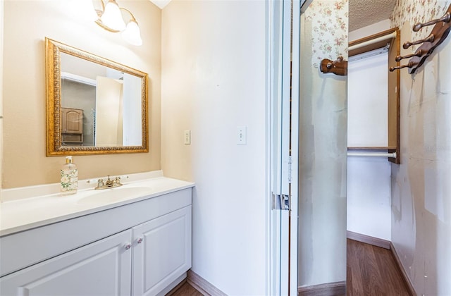 bathroom with hardwood / wood-style floors, vanity, and a textured ceiling