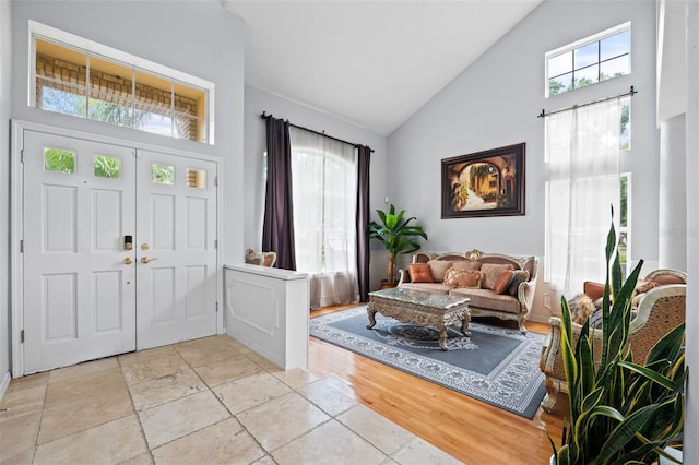 foyer with plenty of natural light, high vaulted ceiling, and light hardwood / wood-style floors